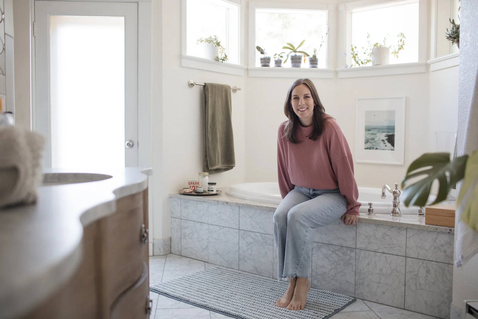 Cally sitting on the edge of a bright bathroom tub