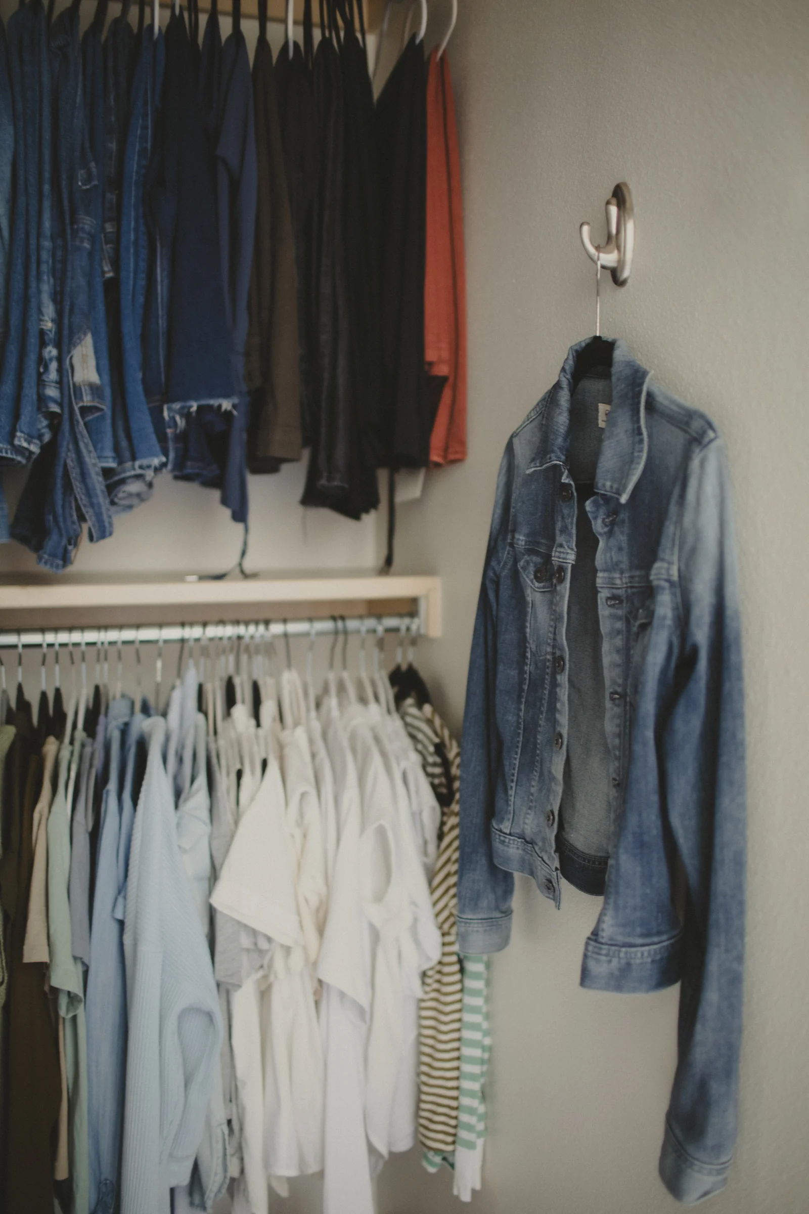 Organized closet with a denim jacket hanging beside it