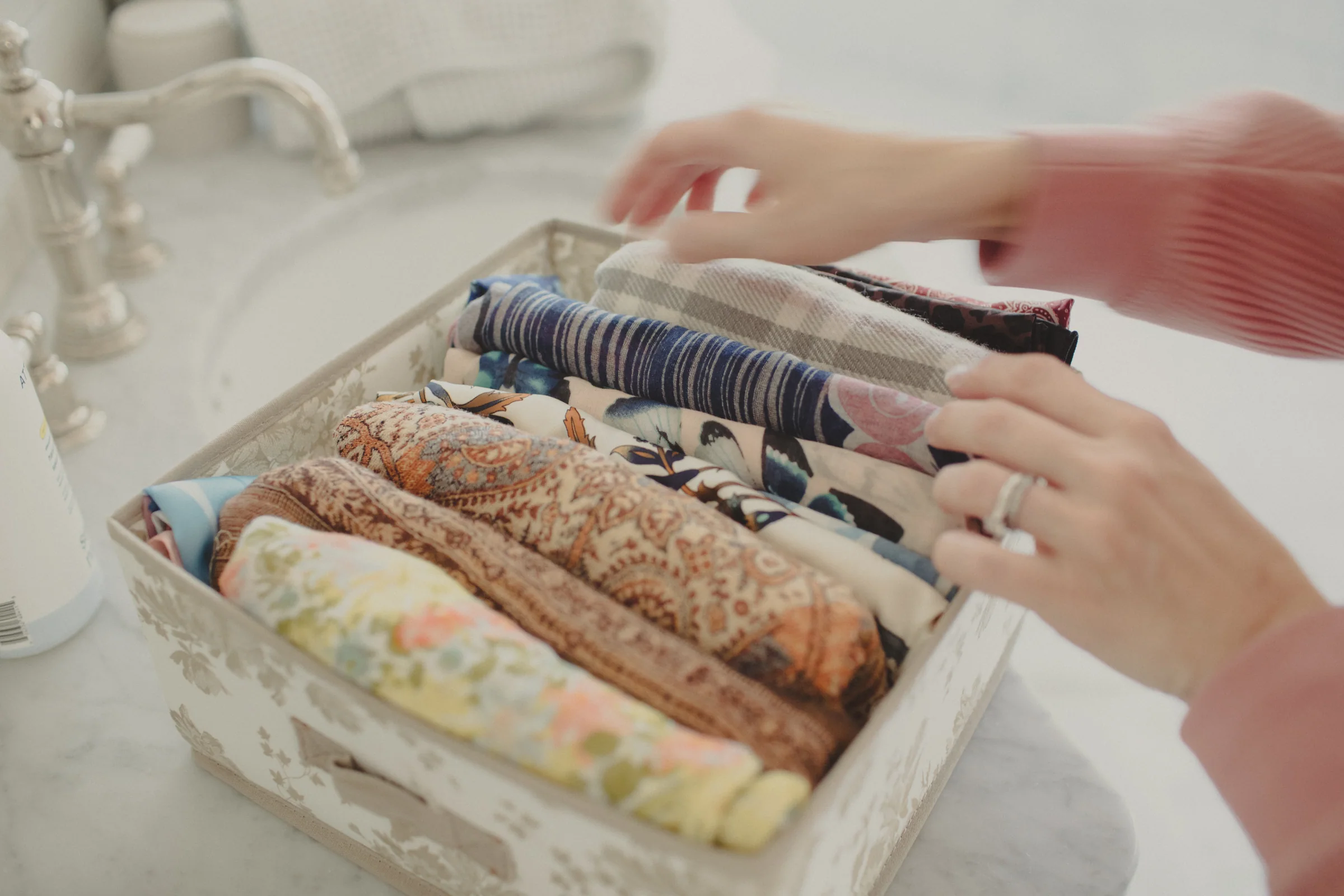 Hands organizing a colorful collection of scarves