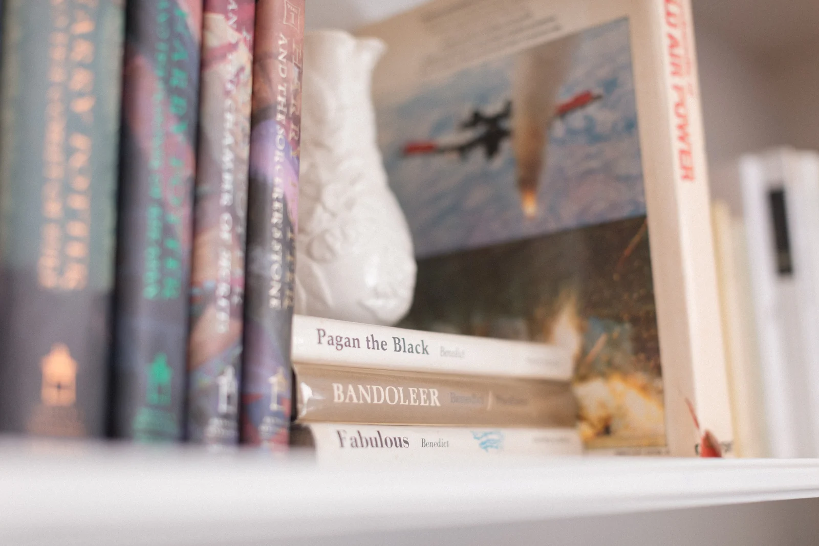 A white vase styled among colorful books